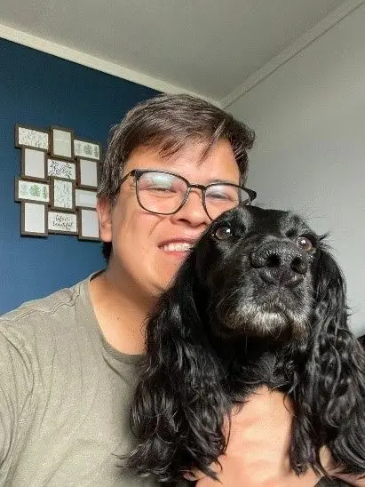 A man smiling with his black spaniel