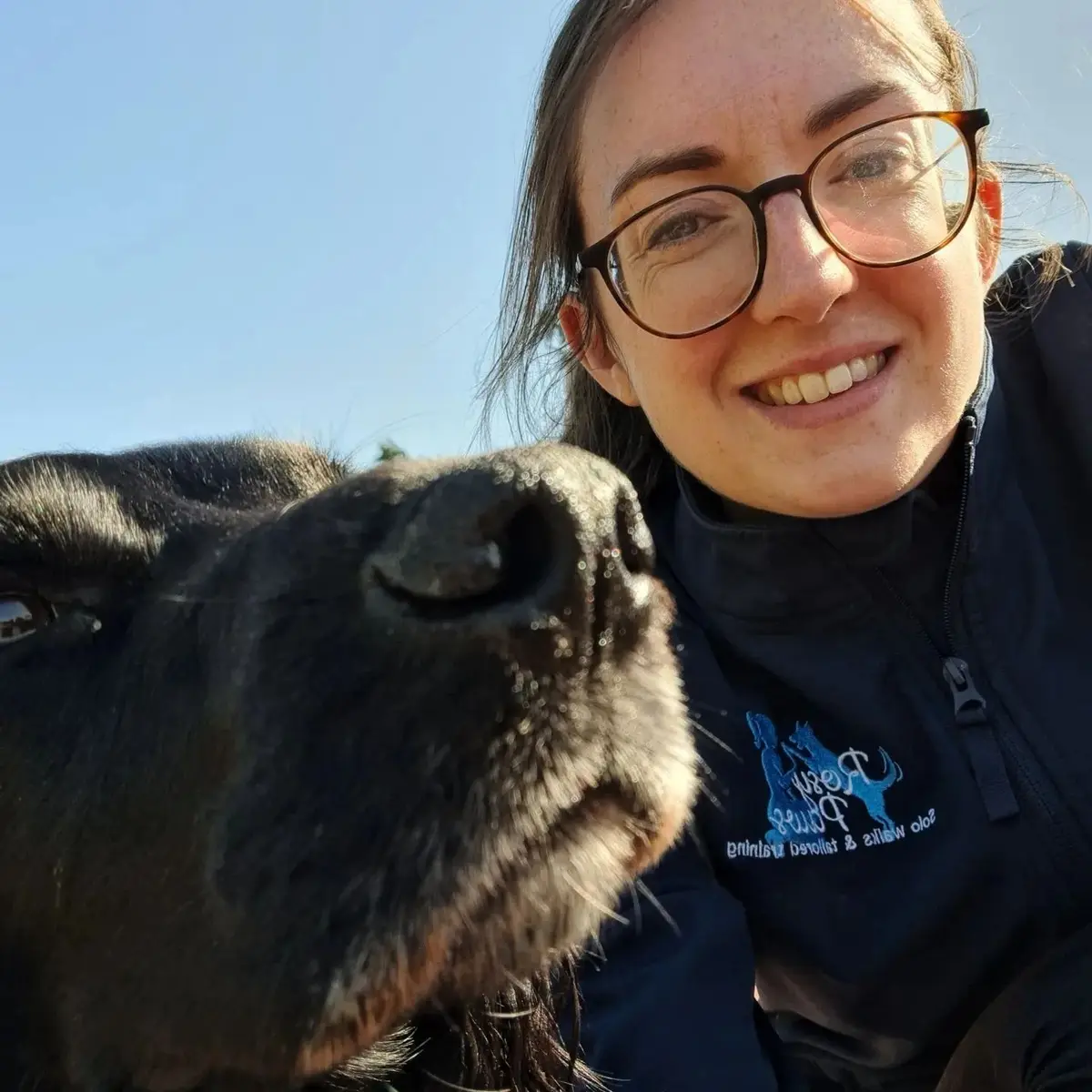Rosy smiling beside a black dog on a sunny day