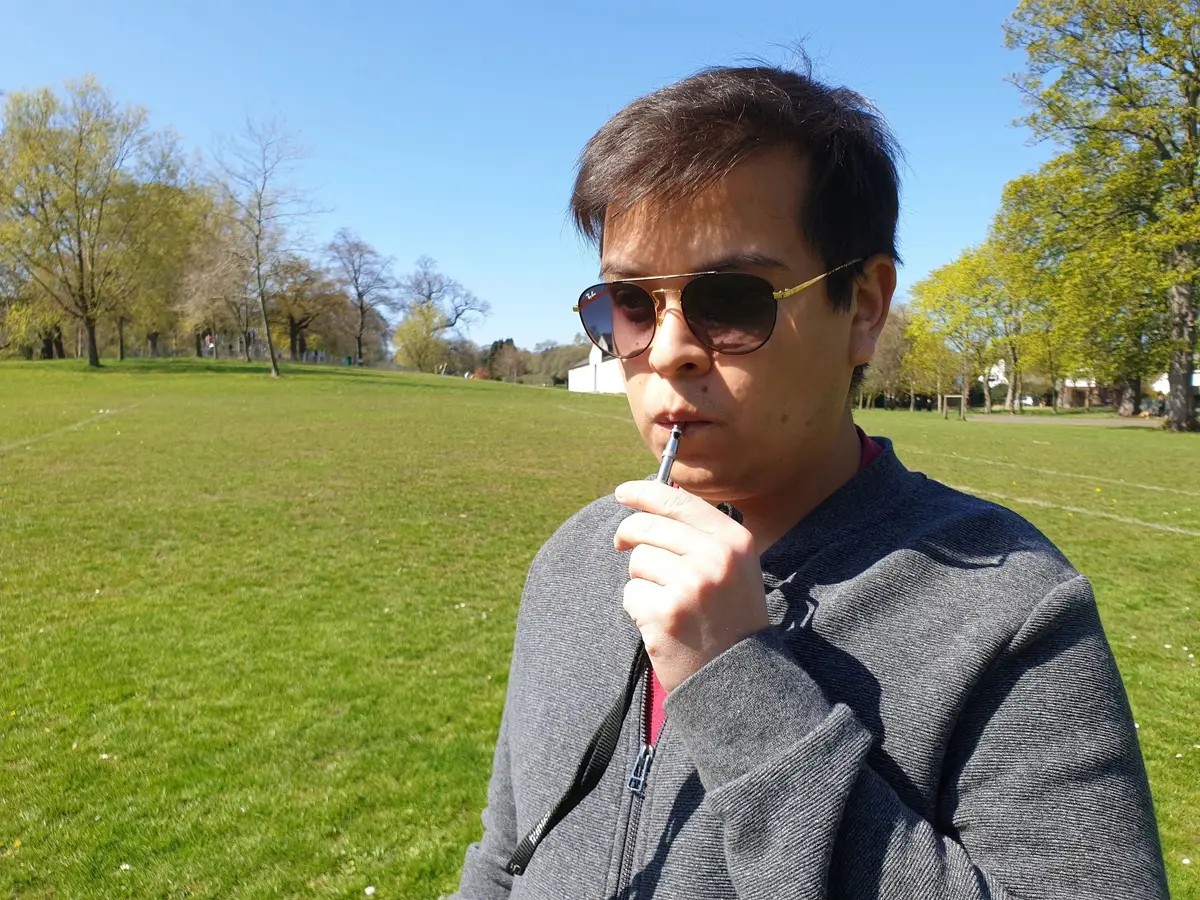 A man blowing a dog whistle in the park