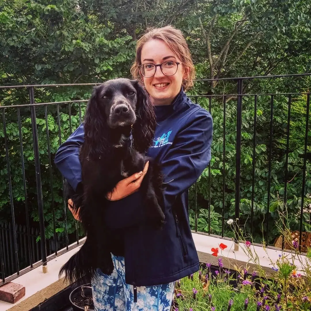 Rosy holding her black spaniel in the garden