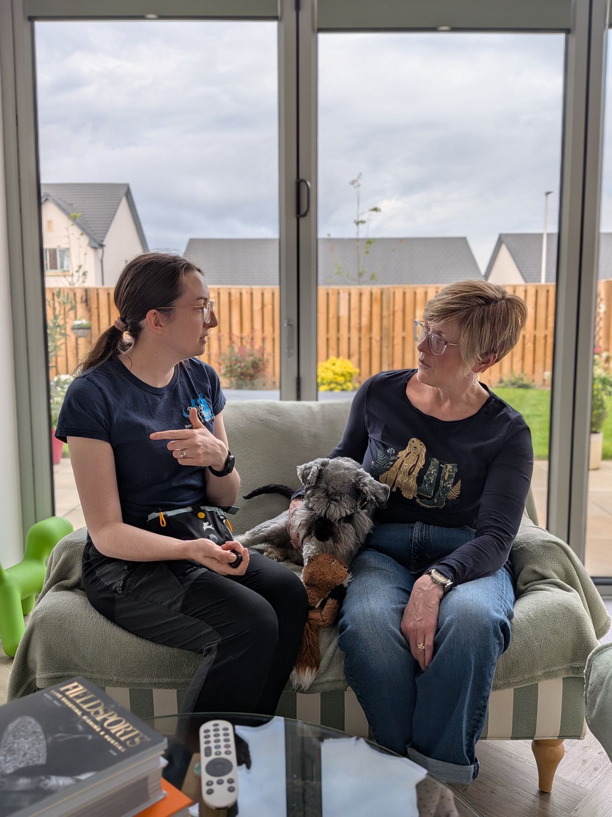 Rosy talking an owner through their training plan at home, with their Schnauzer between them