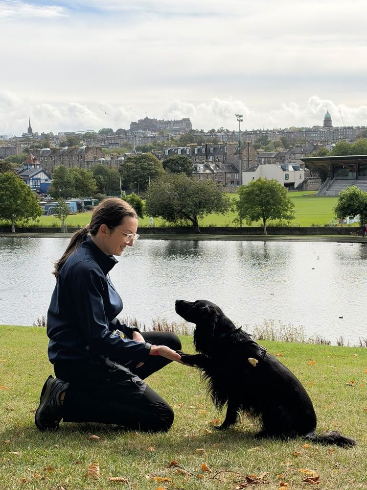 Rosy kneeling by a loch, rewarding her spaniel